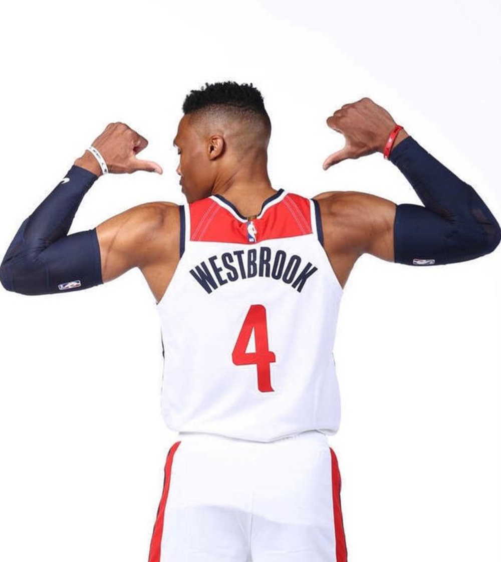 An athlete poses confidently in a white basketball jersey with "WESTBROOK" and the number "4" on the back, showcasing toned muscles.